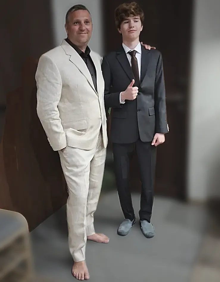 Two customers in finished suits — cream linen and grey worsted — photographed at home after delivery.