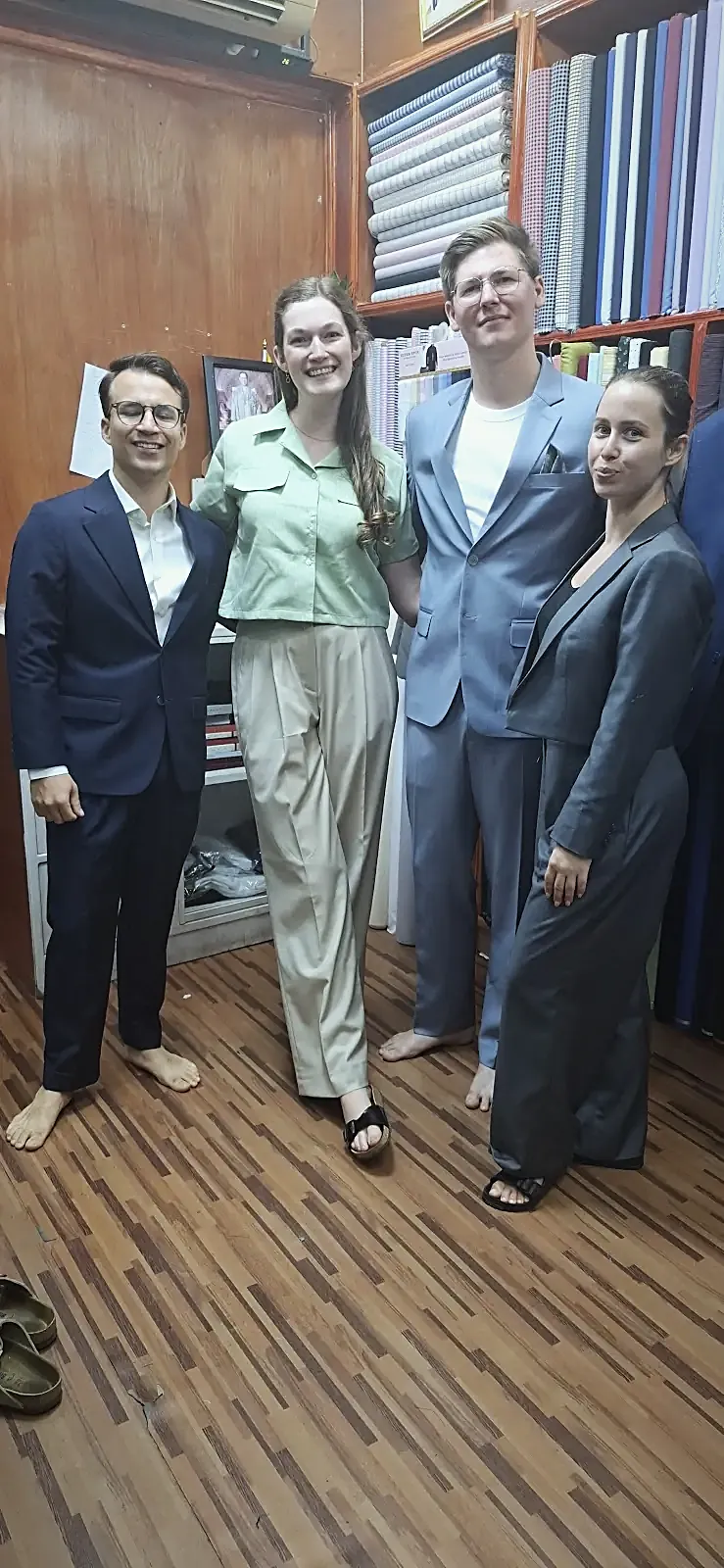 Four suits collected together — navy, pale blue and grey, cut for two women and two men.