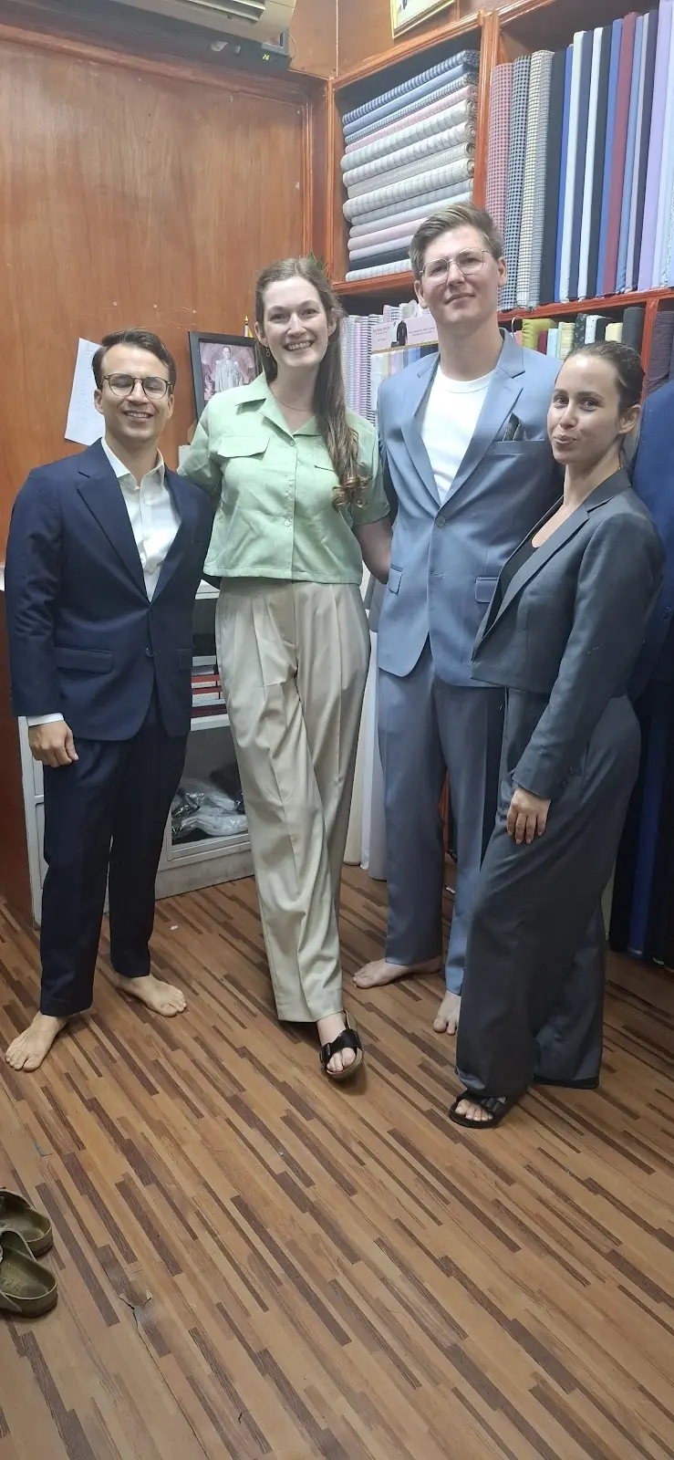 Four suits collected together — navy, pale blue and grey, cut for two women and two men.