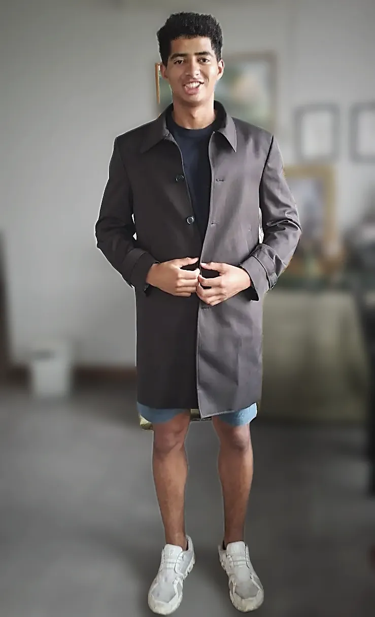A grey overcoat tried on at home, buttoned to check the front.