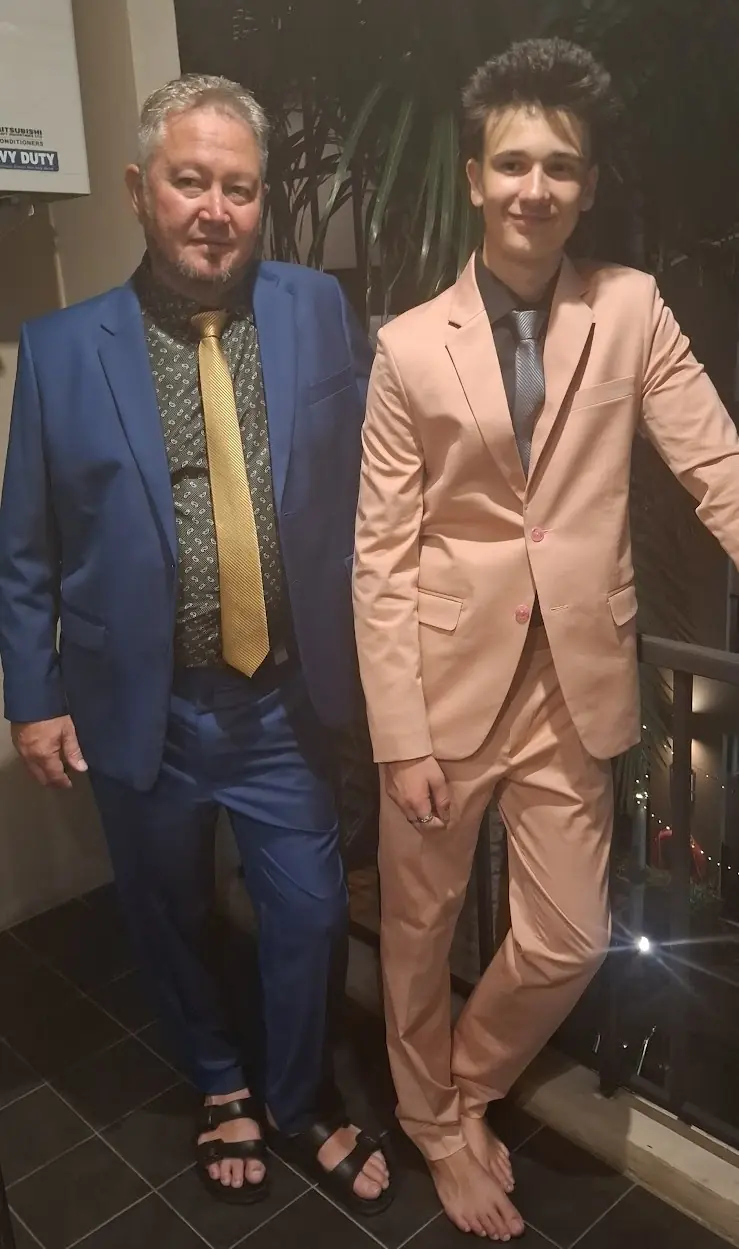 Two finished suits at home: a blue one with a gold tie, and a peach suit cut for a younger wearer.