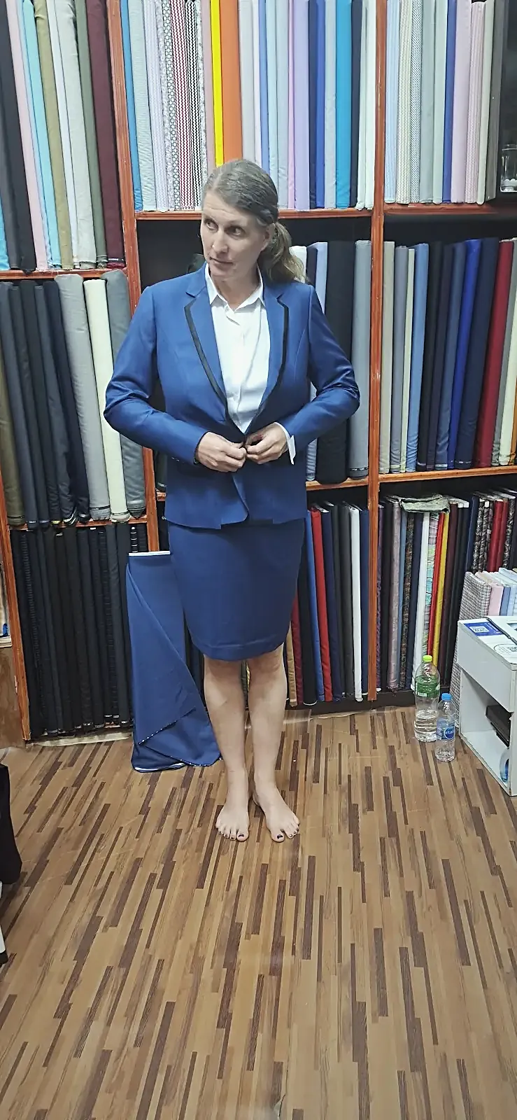 A blue skirt suit at the fitting, the lapels trimmed in black and the fitting tag still on the cuff.