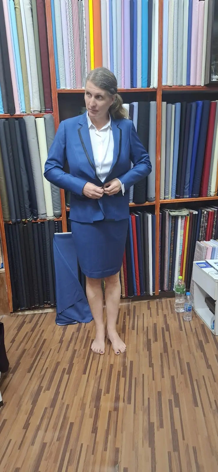 A blue skirt suit at the fitting, the lapels trimmed in black and the fitting tag still on the cuff.