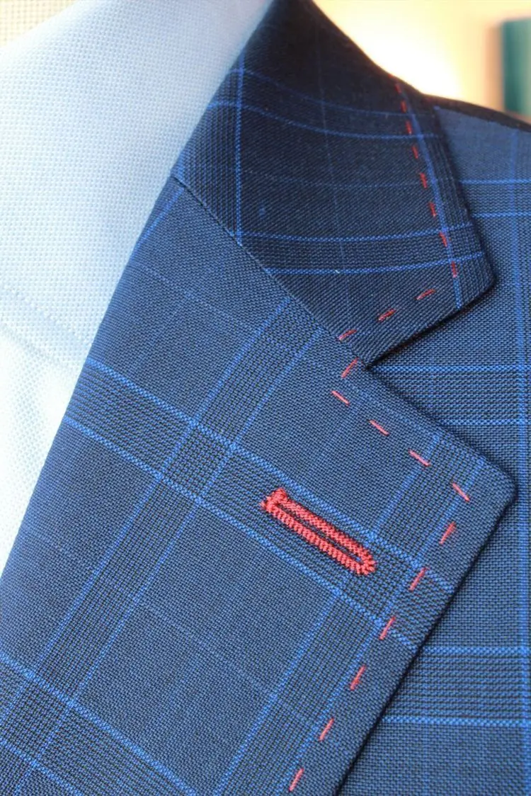 A hand-finished buttonhole and pick-stitching in red on navy glen check.