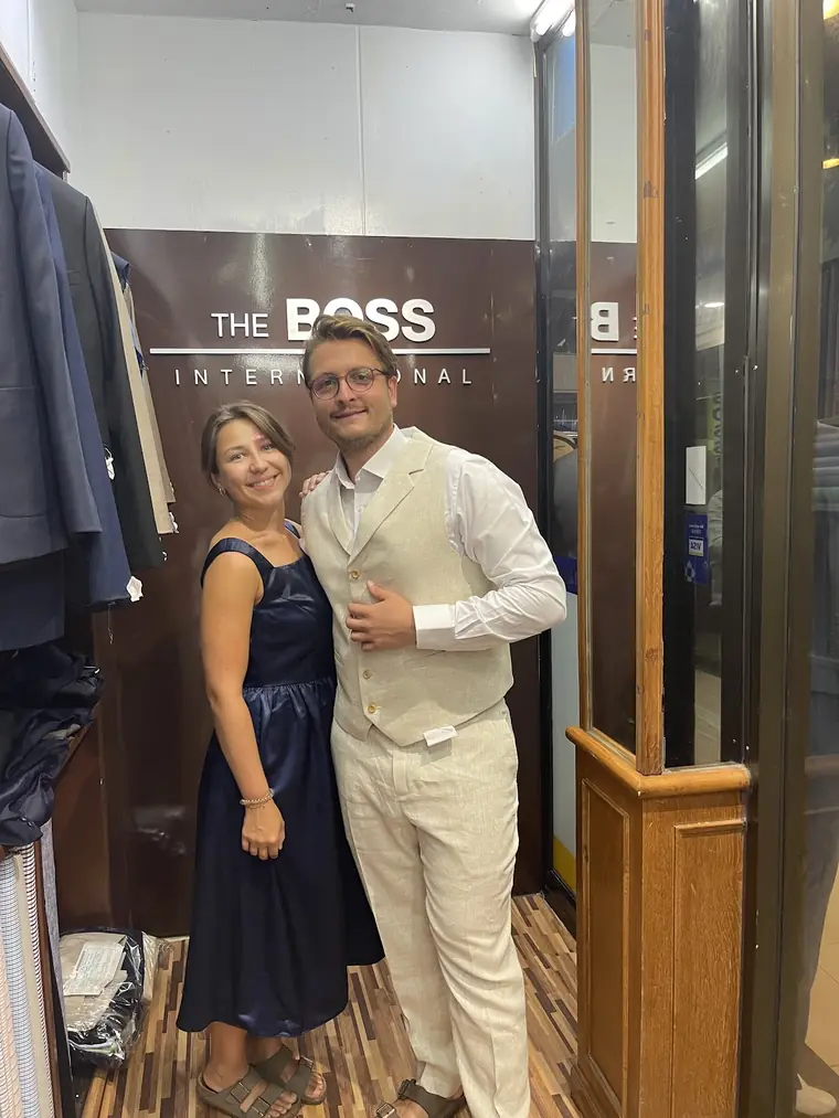 The suit and the dress the review says were finished together: a cream linen waistcoat and trousers, and a navy satin dress, under The Boss International sign.