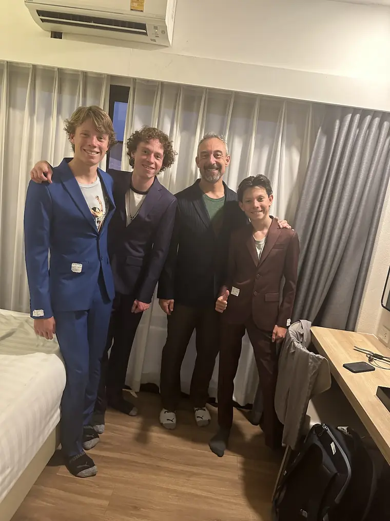 Four new suits worn in a hotel room — bright blue, purple, black and burgundy — with the maker’s tags still attached to the sleeves.