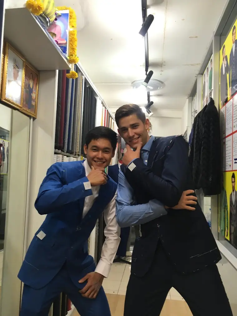 Two new suits with the maker’s tags still on them, one bright blue and one navy, photographed in the fitting aisle.