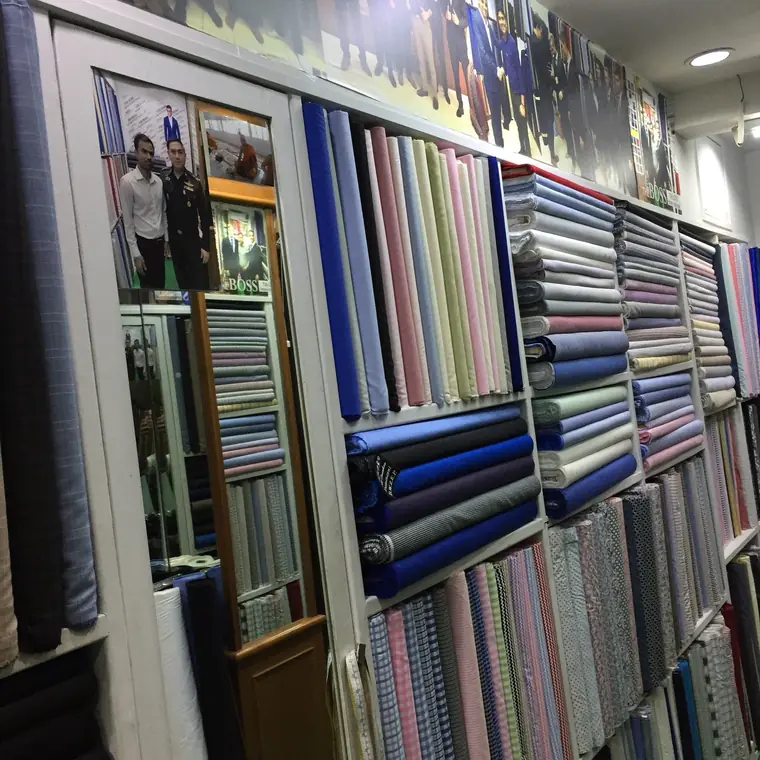 Shelves of shirting stacked by colour, with a long mirror set into the wall of cloth.