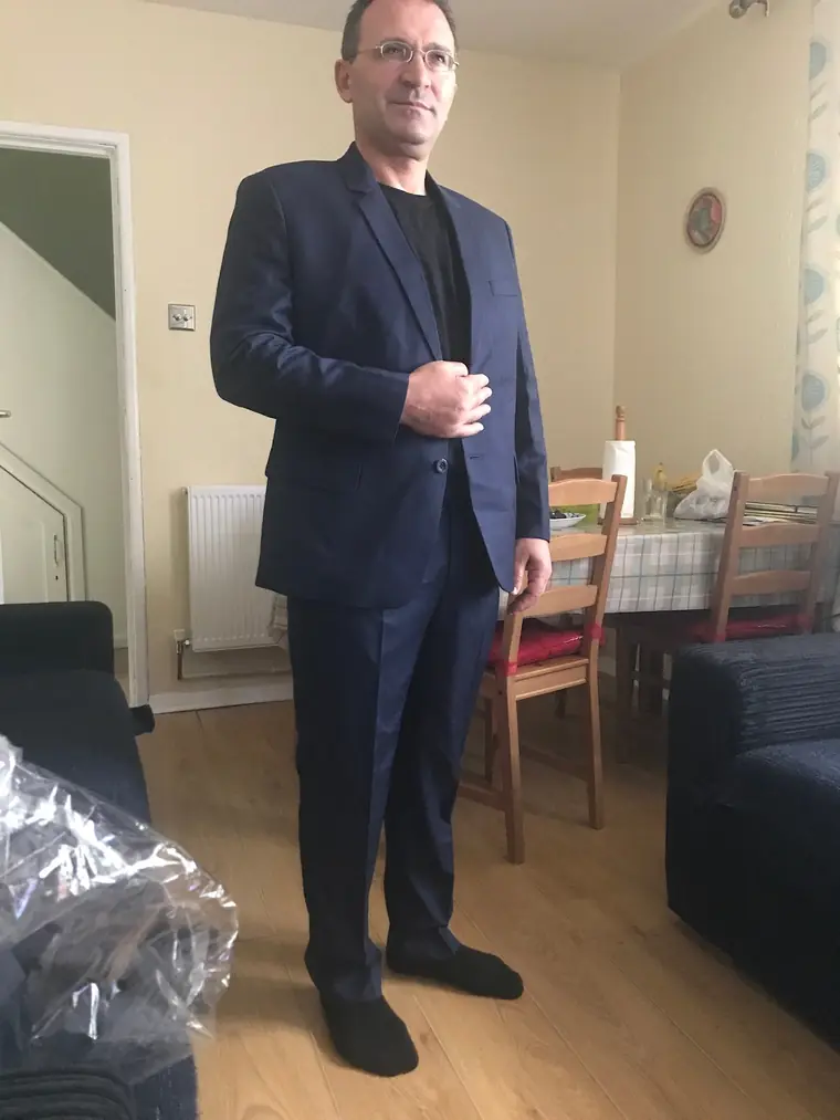 The reviewer wearing the navy suit they had made, photographed at home after it arrived.
